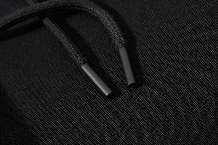 Close-up of black drawstring cords with metal tips on textured sweatpant fabric
