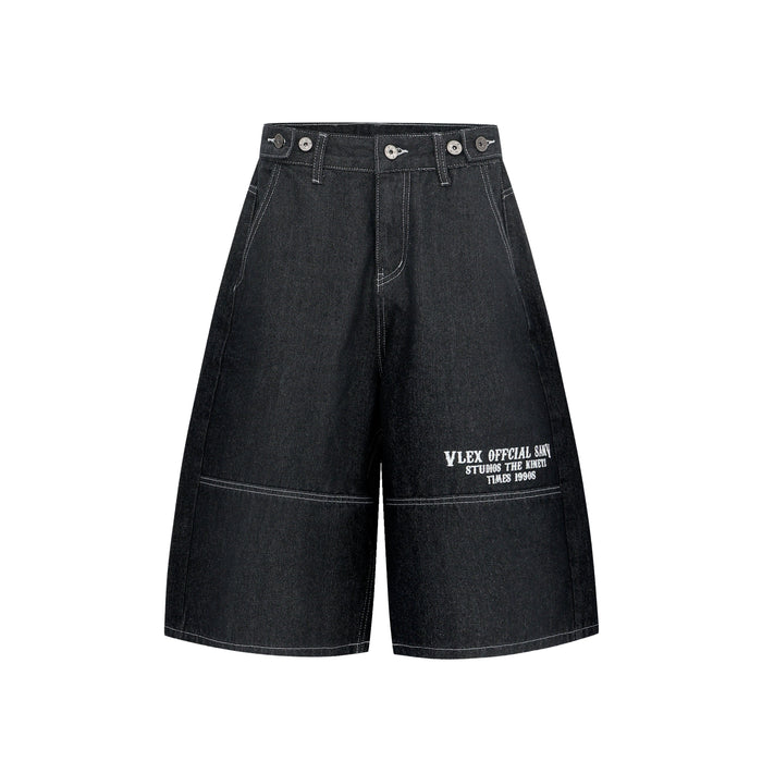 Black oversized denim shorts front view with wide legs and white printed hem text