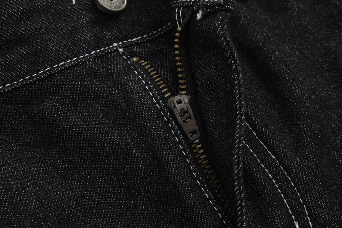Extreme close-up of black denim zipper fly and seam stitching