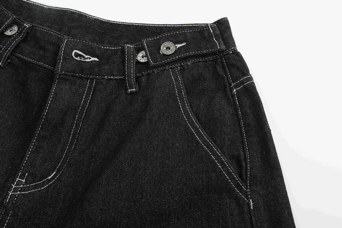 Front waistband and pocket area of black denim shorts with button fly details