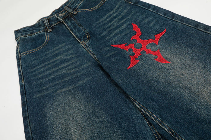 Dark blue denim front close-up showing a red embroidered Gothic emblem and faded texture