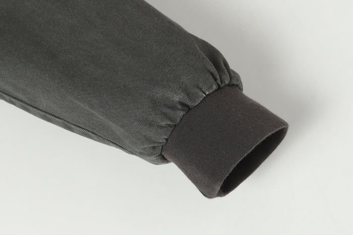 Close-up of a gray bomber jacket sleeve with gathered stitching and a dark ribbed cuff