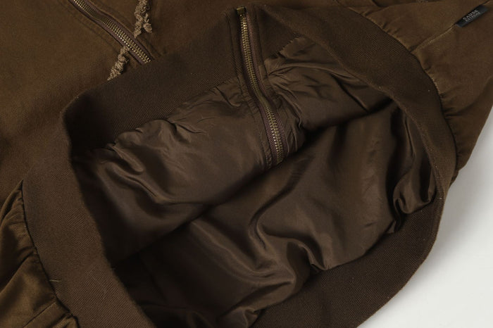 Close-up of the brown bomber jacket interior showing smooth dark lining, zipper and ribbed waistband