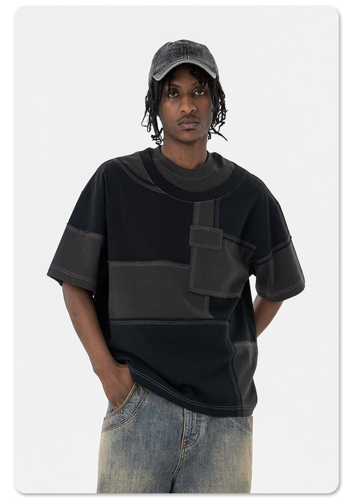 Black oversized patchwork panel T-shirt with contrast stitching, worn by a male model in streetwear style