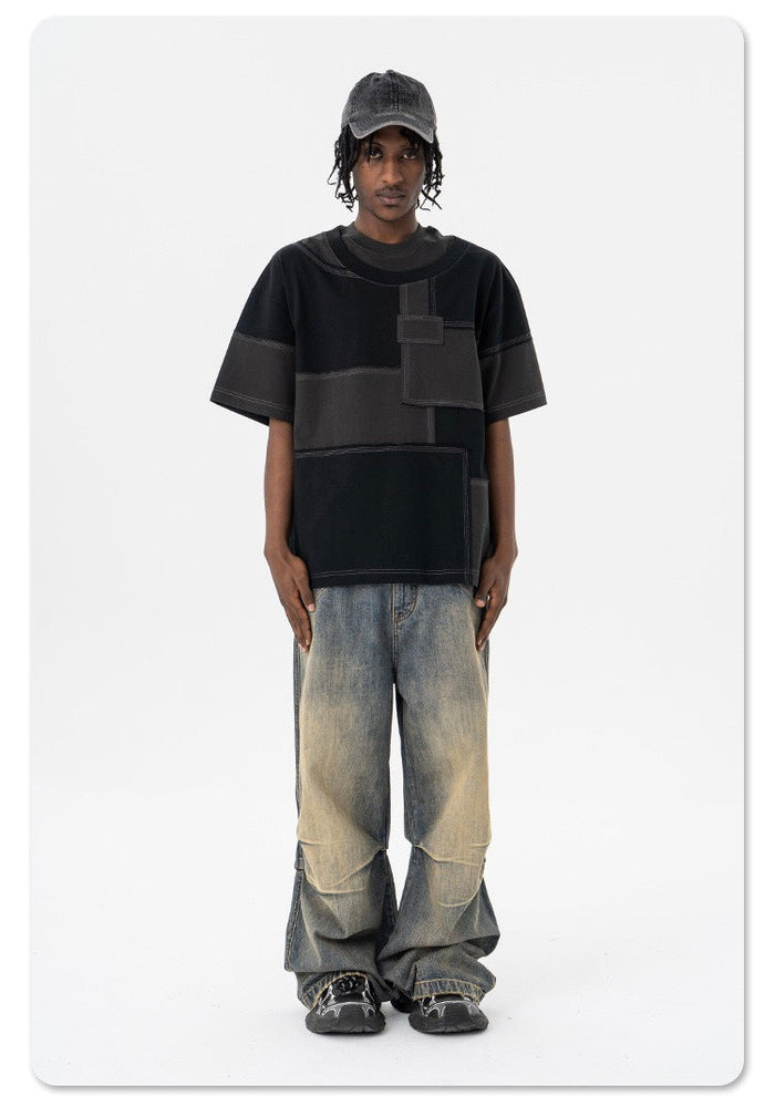 Black oversized patchwork T-shirt with deconstructed panel design styled with baggy faded jeans and a black cap