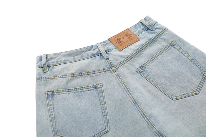 Back waist detail of distressed light blue denim skirt shorts with leather patch and pockets