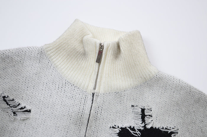 Close-up of a light gray knit cardigan showing its cream ribbed high collar and front zipper