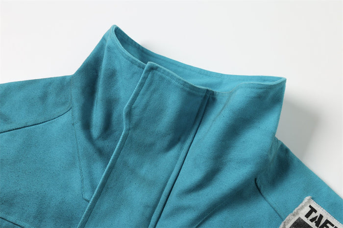 Close-up of teal high collar and shoulder seam with distressed wash and patch detail at side