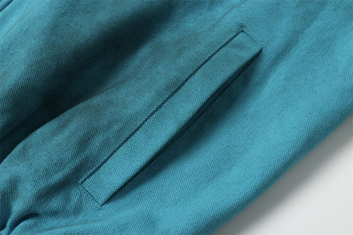 Teal bomber jacket sleeve pocket detail on textured fabric