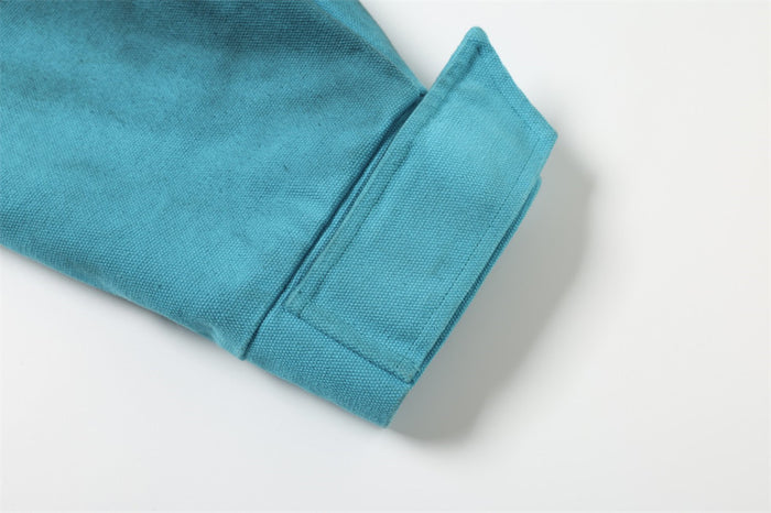 Teal jacket cuff with stitched tab detail on the sleeve hem