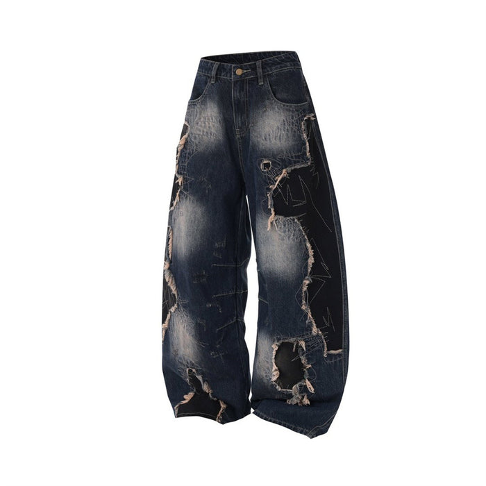 Angled front view of dark blue baggy jeans featuring wide legs, faded denim, black patchwork, and ripped lower legs