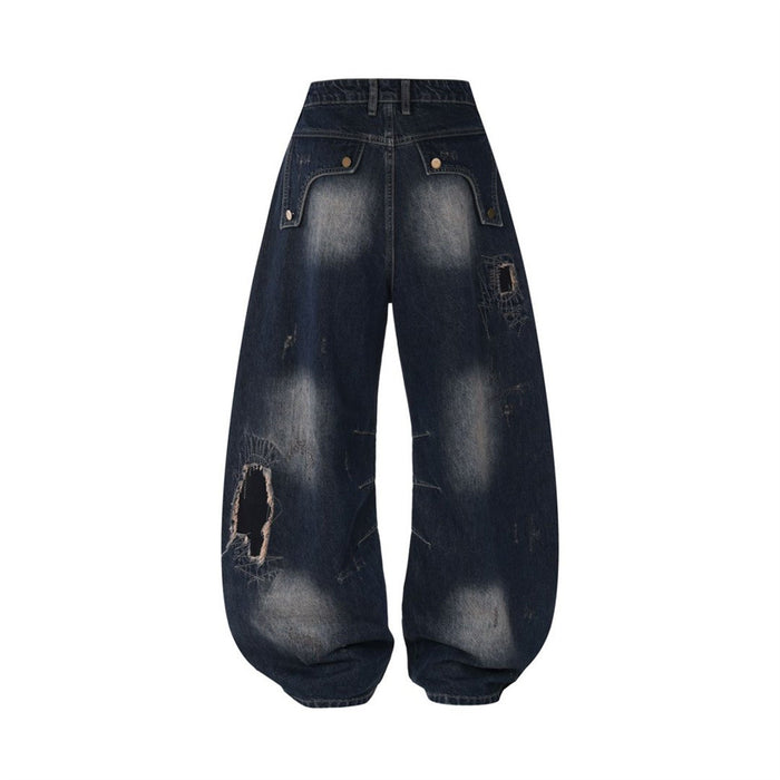 Back view of dark blue wide-leg jeans with faded areas, flap pockets, rounded hems, and a distressed thigh patch