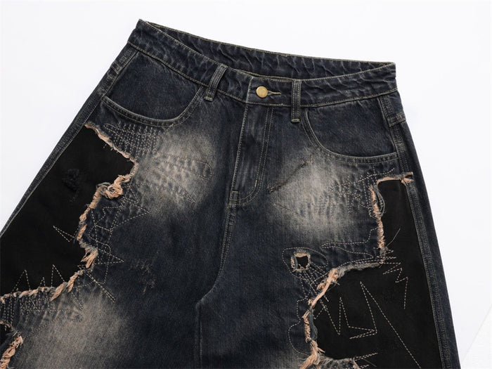 Close-up of the jeans front showing the waistband, pockets, faded denim, stitched patchwork, and frayed ripped panels