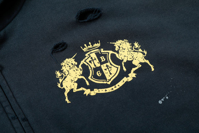 Close-up of a gold heraldic crest with lions and shield printed on the distressed navy fabric