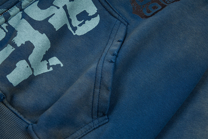 Close-up of the washed blue hoodie pouch pocket, front graphic, and textured sleeve