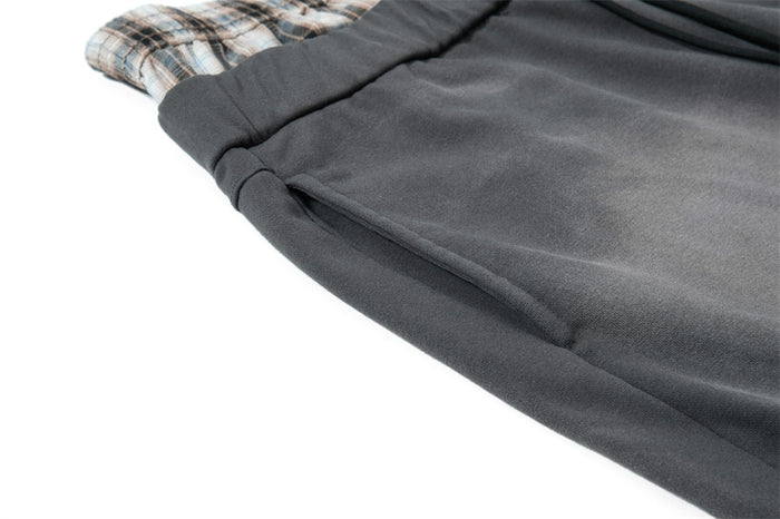 Close-up of side seam and pocket on gray sweatpants with plaid waistband