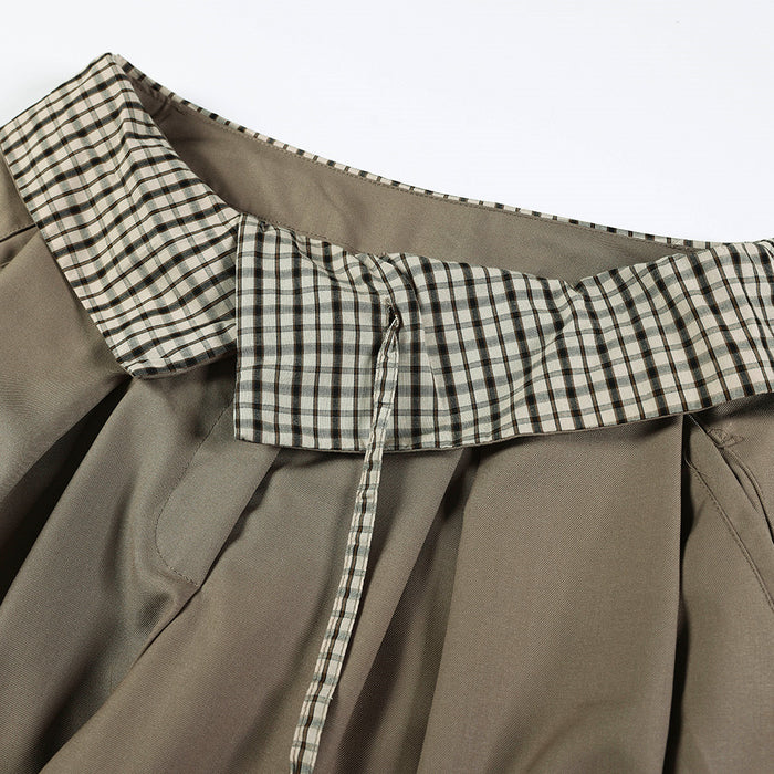 Close-up of gingham fold-over waistband and front seam on taupe trousers