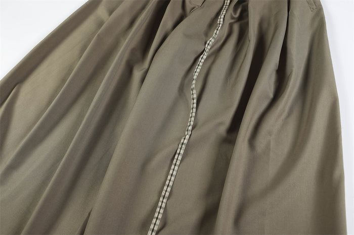 Close-up of taupe trouser fabric with center seam and draped pleats
