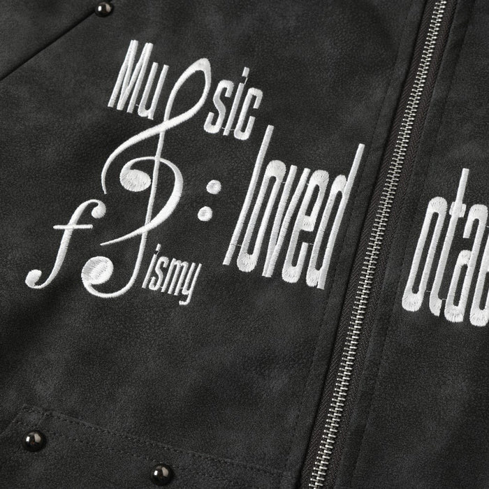 Close-up of white embroidered lettering and music note graphic on black jacket