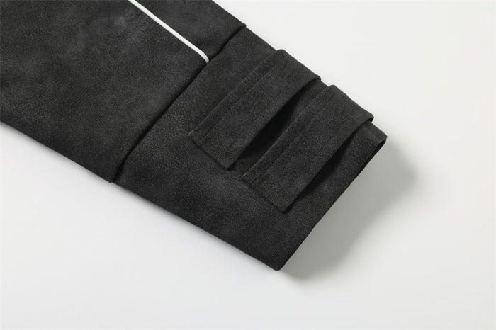 Close-up of black jacket cuff with stitched strap tabs and snap buttons