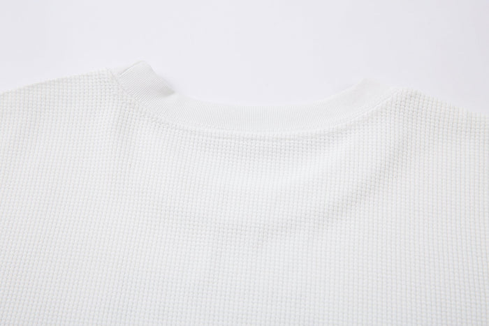 Close-up of white waffle-knit crewneck collar and shoulder seam