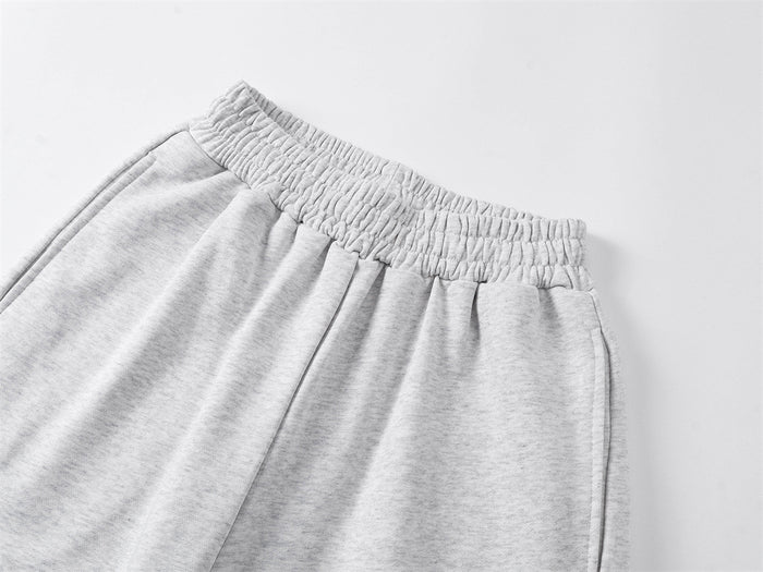 Close-up of the ruched elastic waistband and gathered fabric on light gray sweatpants
