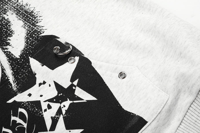 Close-up of a black graphic panel with star shapes, metal ring detail, and snap fasteners on the grey hoodie
