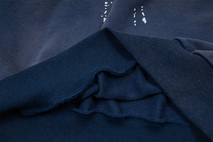 Close-up of the navy sweatshirt's ribbed hem and distressed fabric layers showing the textured knit construction