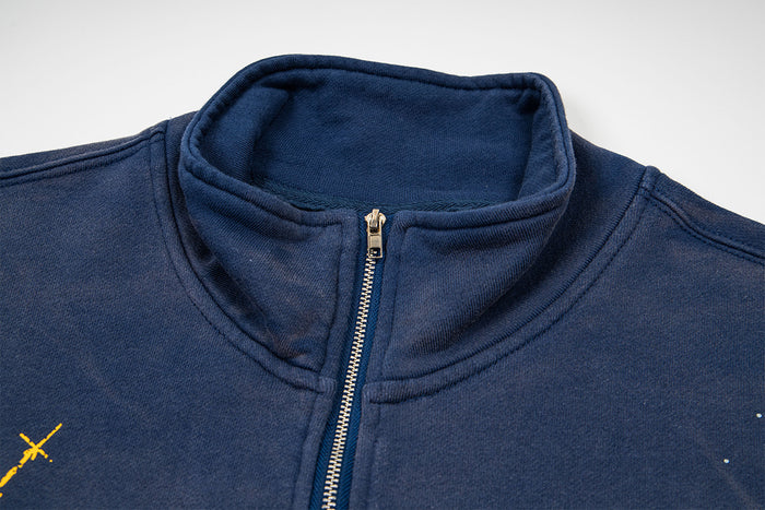 Close-up of the navy sweatshirt's stand collar with a gold-toned half-zipper and visible stitched edges