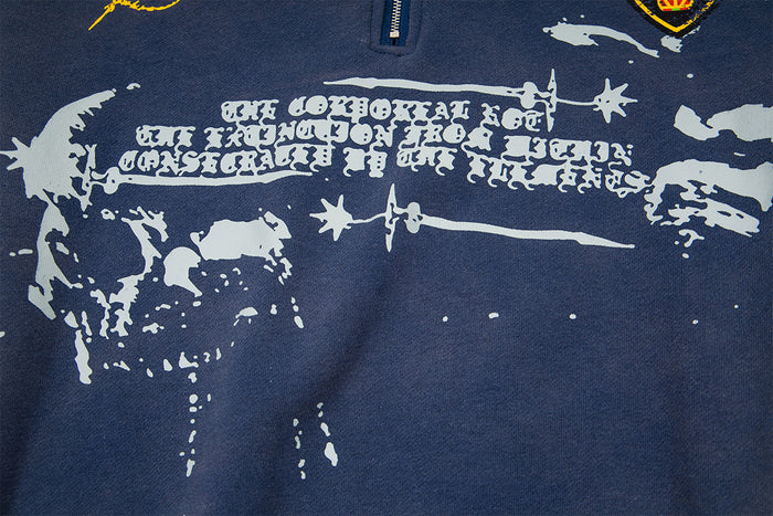 Close-up of the navy sweatshirt chest showing a distressed white gothic text and abstract graphic print