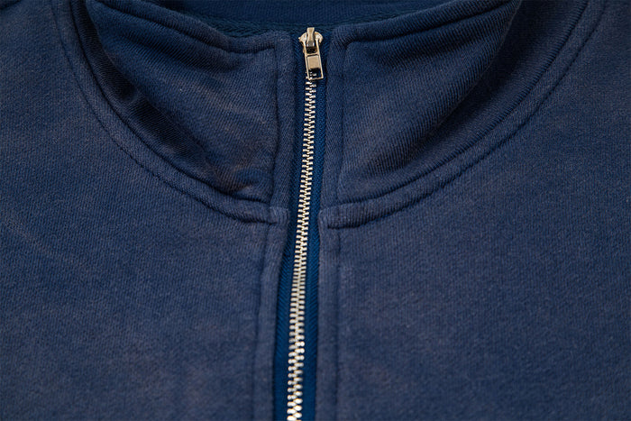 Detailed view of the navy sweatshirt's gold-toned zipper, stand collar, and textured fabric around the neckline