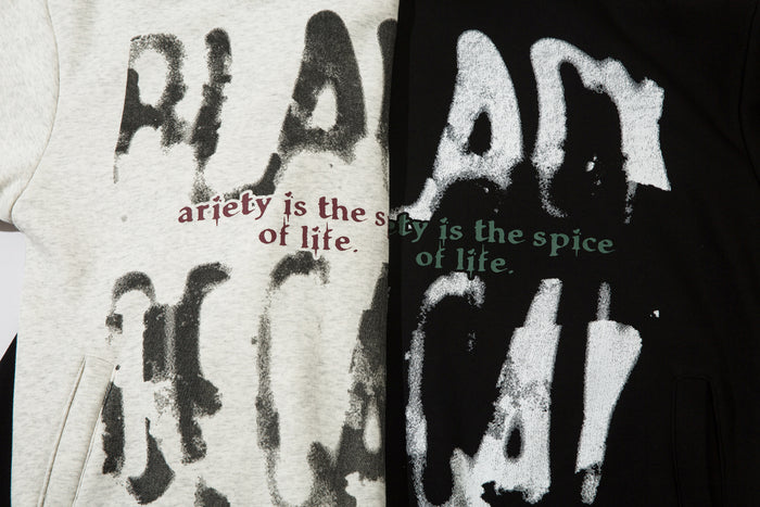 Close-up of distressed graffiti lettering and contrasting red and green slogan text on gray and black hoodies