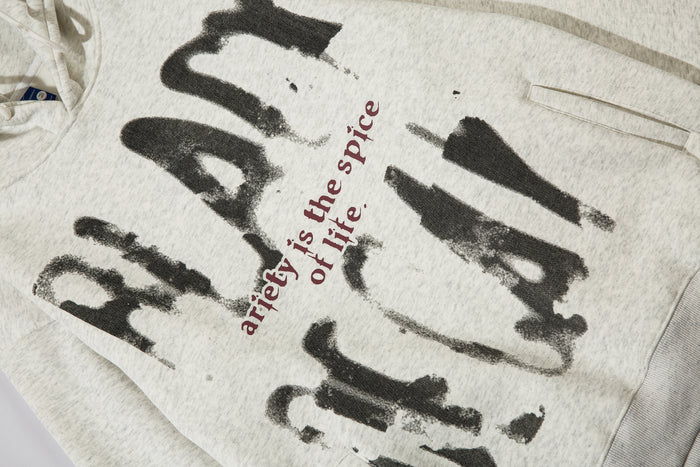Angled close-up of the gray hoodie front showing distressed lettering, slogan text, and pocket seam