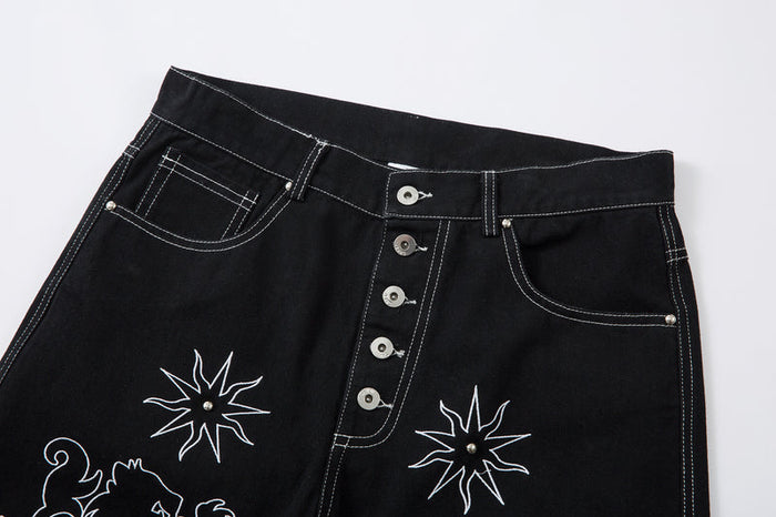 Front waist of black jeans with button fly, curved pockets, and white contrast stitching