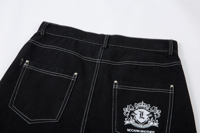 Back waist of black jeans with two patch pockets and embroidered crest on right pocket