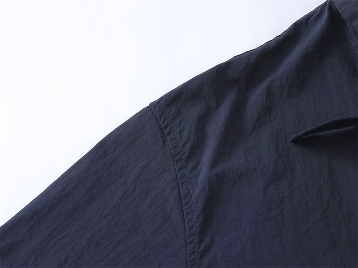Close-up of navy overshirt shoulder seam and matte fabric texture