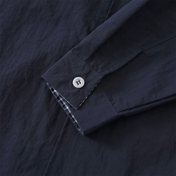 Close-up of sleeve cuff with button and plaid inner cuff detail
