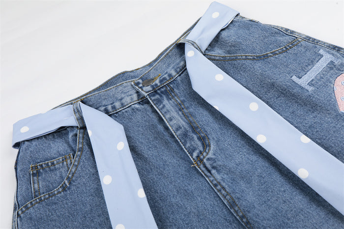 Close-up of light wash denim shorts waistband with pale blue polka dot tie belt