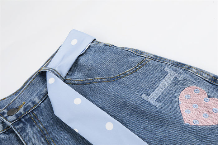 Close-up of light wash denim shorts upper front with polka dot tie belt and heart print detail