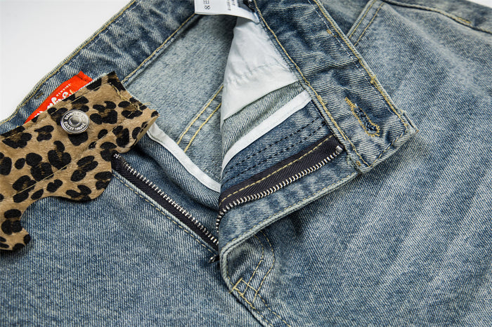 Close-up of front waistband, button, and zipper on light wash denim shorts