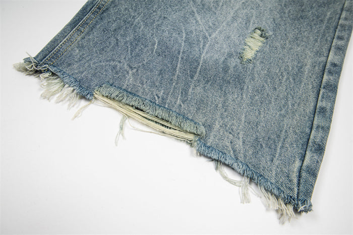 Close-up of frayed hem and ripped edge on light wash denim shorts