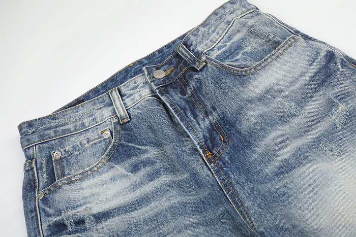 Close-up of the jeans front waistband, belt loops, button closure and faded blue denim texture