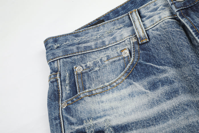 Close-up of a front pocket on light blue washed jeans with contrast stitching and faded denim