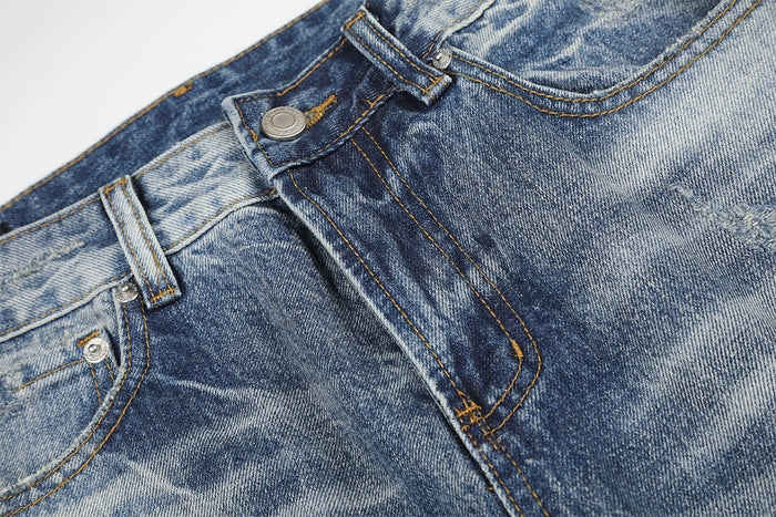 Detailed view of the jeans waistband, belt loop, metal button and stitched front fly