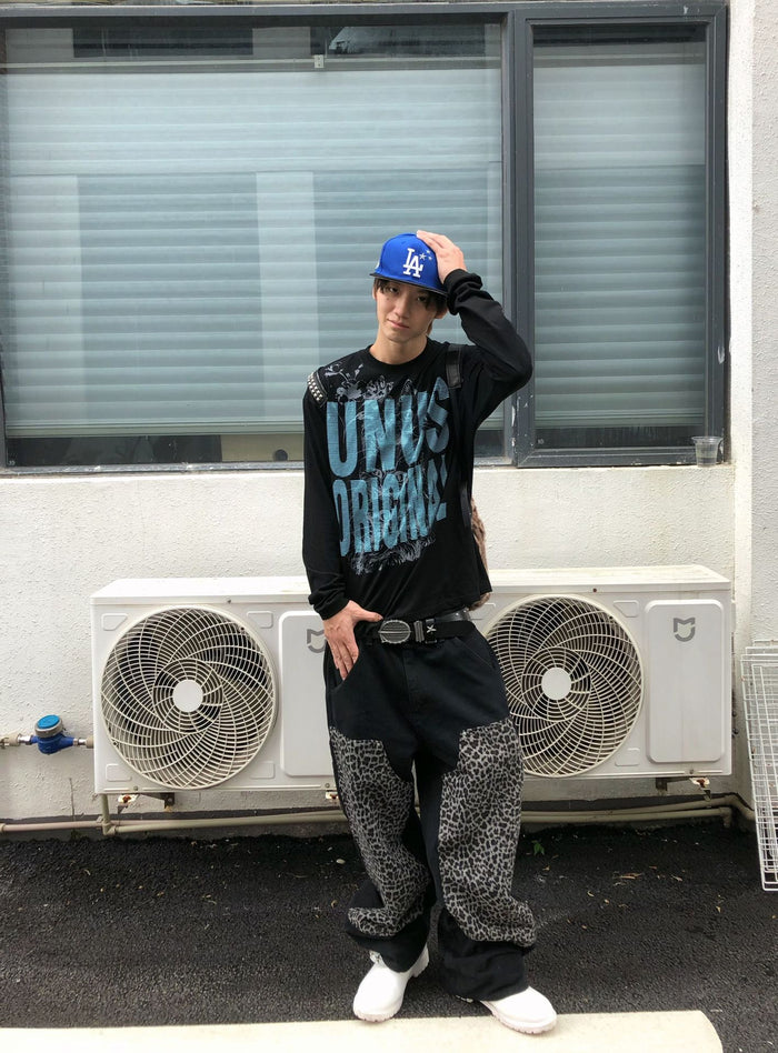Front view of a model wearing a black long sleeve shirt with a blue cat graphic and text