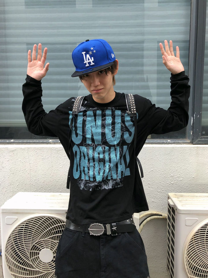 Model raising both hands while wearing a black long sleeve shirt with a blue UNUS cat print