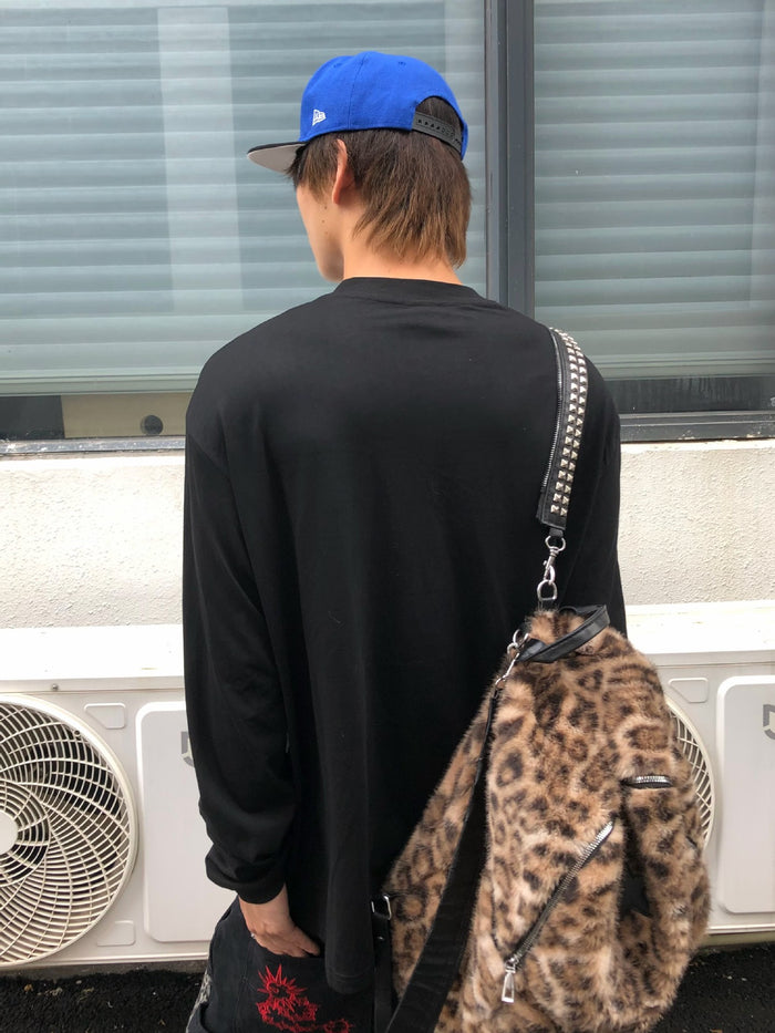 Back view of a model wearing the plain black reverse side of a long sleeve graphic shirt