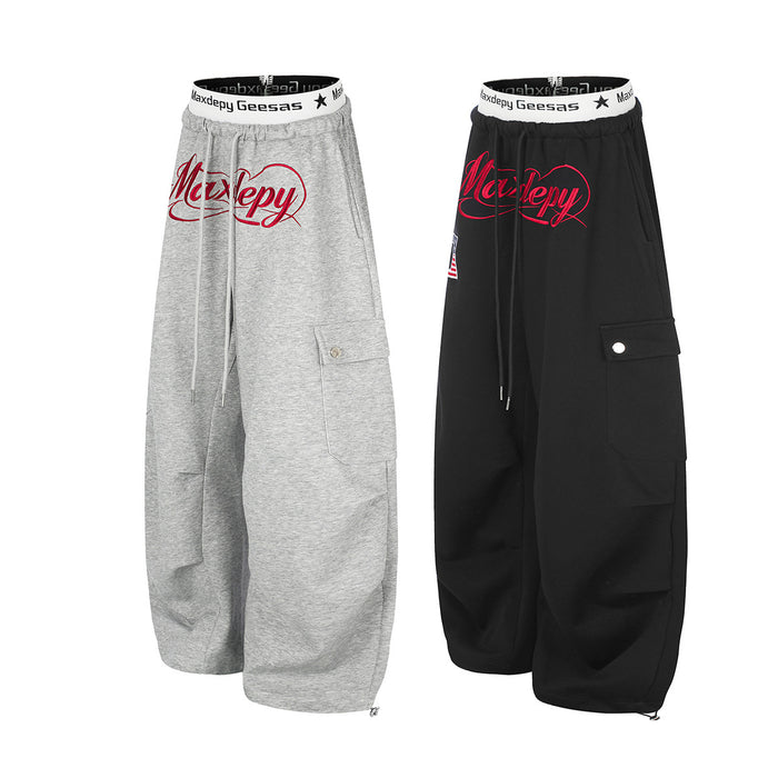 Gray and black wide-leg cargo sweatpants shown in angled front views with red script graphics