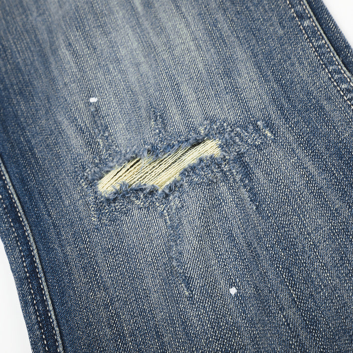 Close-up of a ripped knee on blue distressed denim with exposed threads