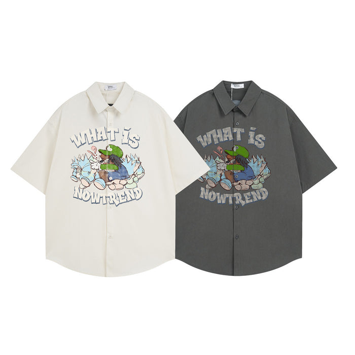 Oversized button-down shirt shown in cream and charcoal, each with a cartoon graphic on the front
